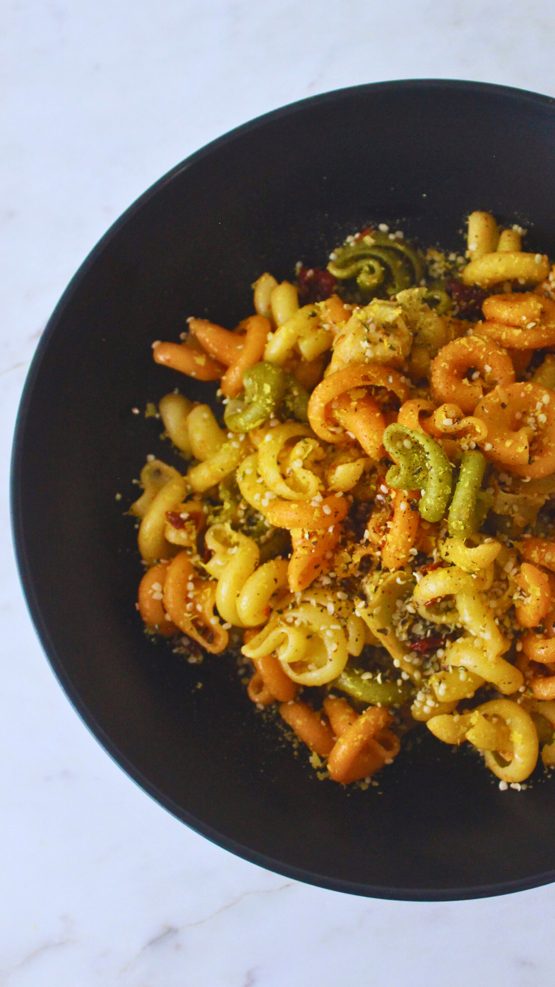 overhead partial image of lemon sundried tomato pasta in a black bowl