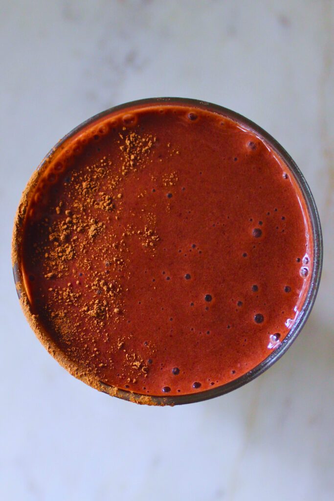 overhead image of a vegan red velvet smoothie topped with cocoa powder