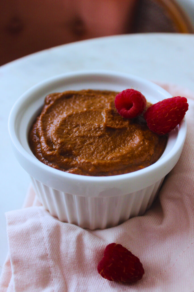 sweet potato chocolate pudding in a ramekin topped with raspberries