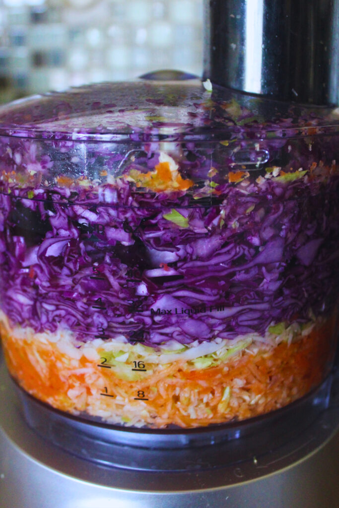 image of shredded carrot and cabbage in a food processor