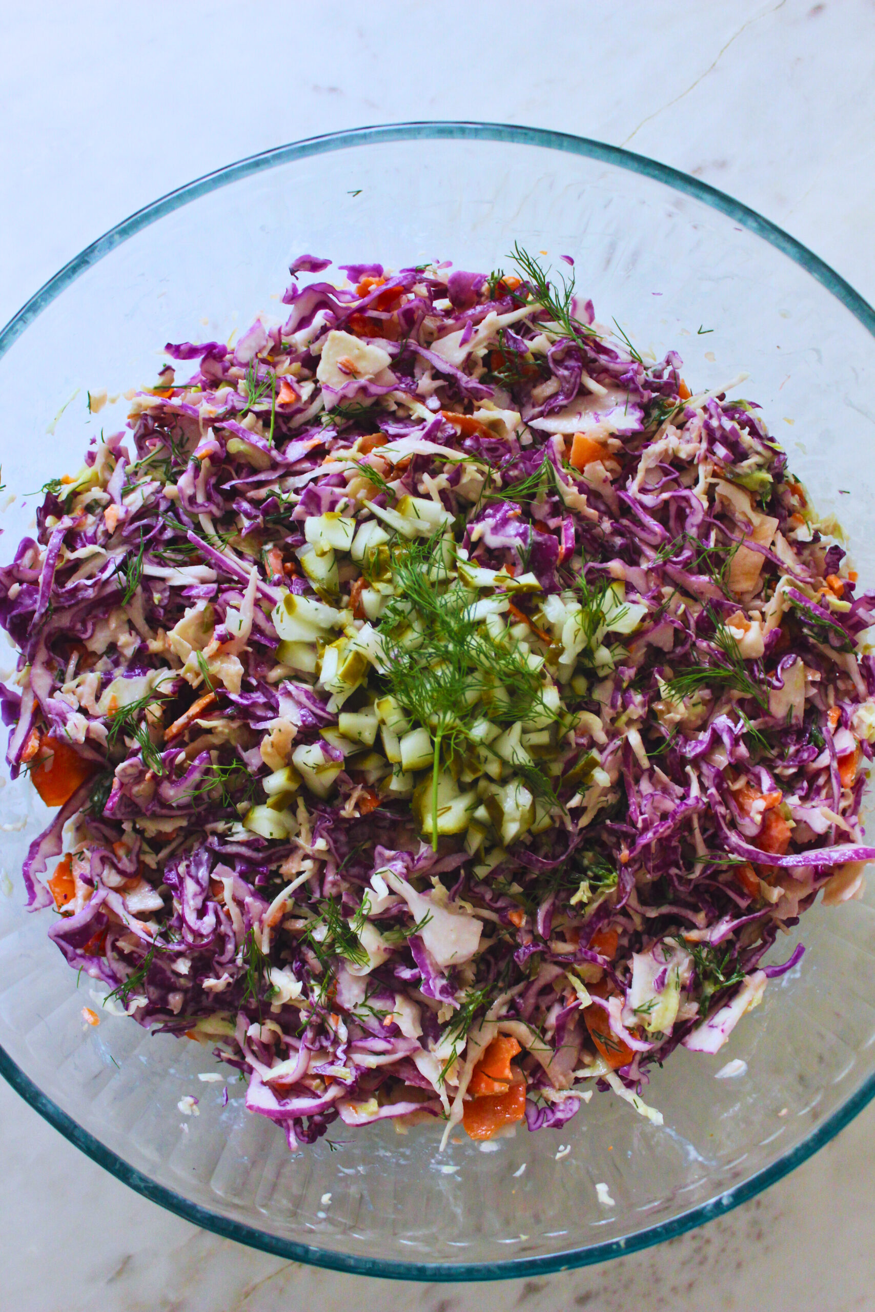overhead image of a large glass bowl of dill pickle coleslaw