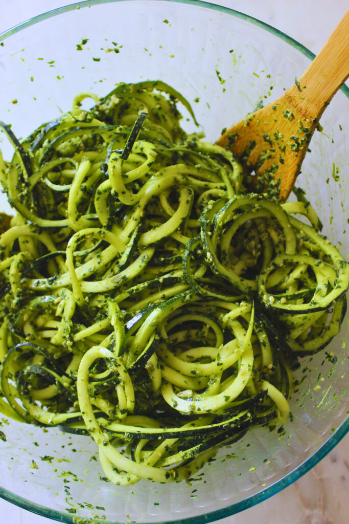 image of raw zucchini noodles with pesto in a large glass bowl