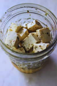 tofu feta cubes seasoned in a glass jar