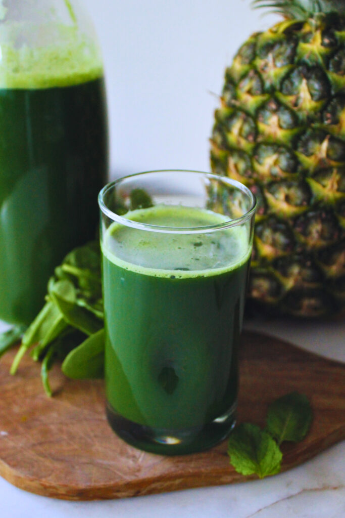 image of a glass of cold pressed green juice with fresh pineapple, spinach, mint leaves