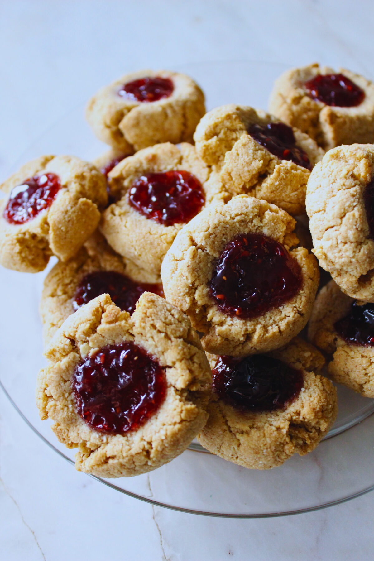 plate full of thumbprint cookies with berry jam filling