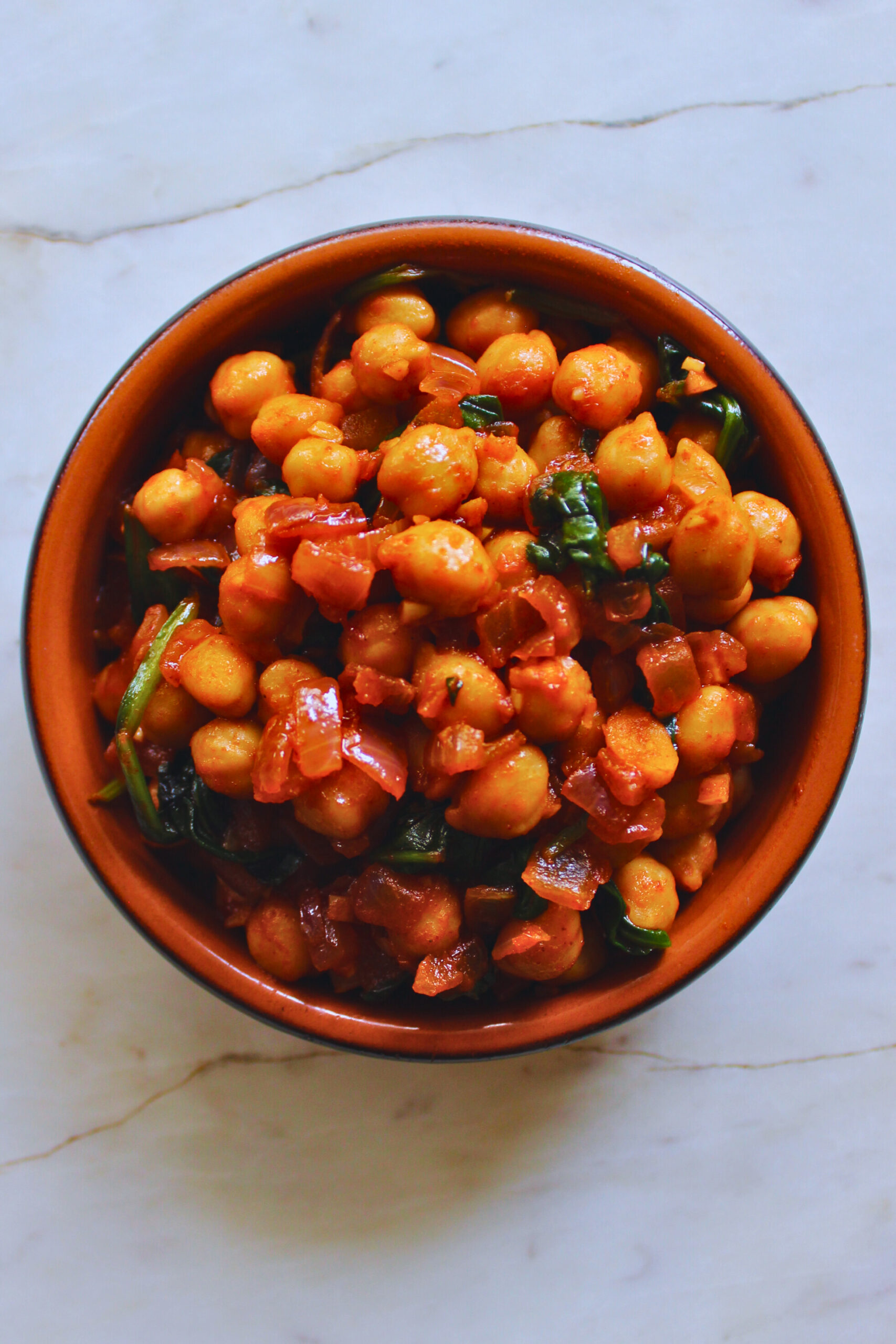 overhead image of chickpeas and spinach served in a Spanish ceramic tapa dish