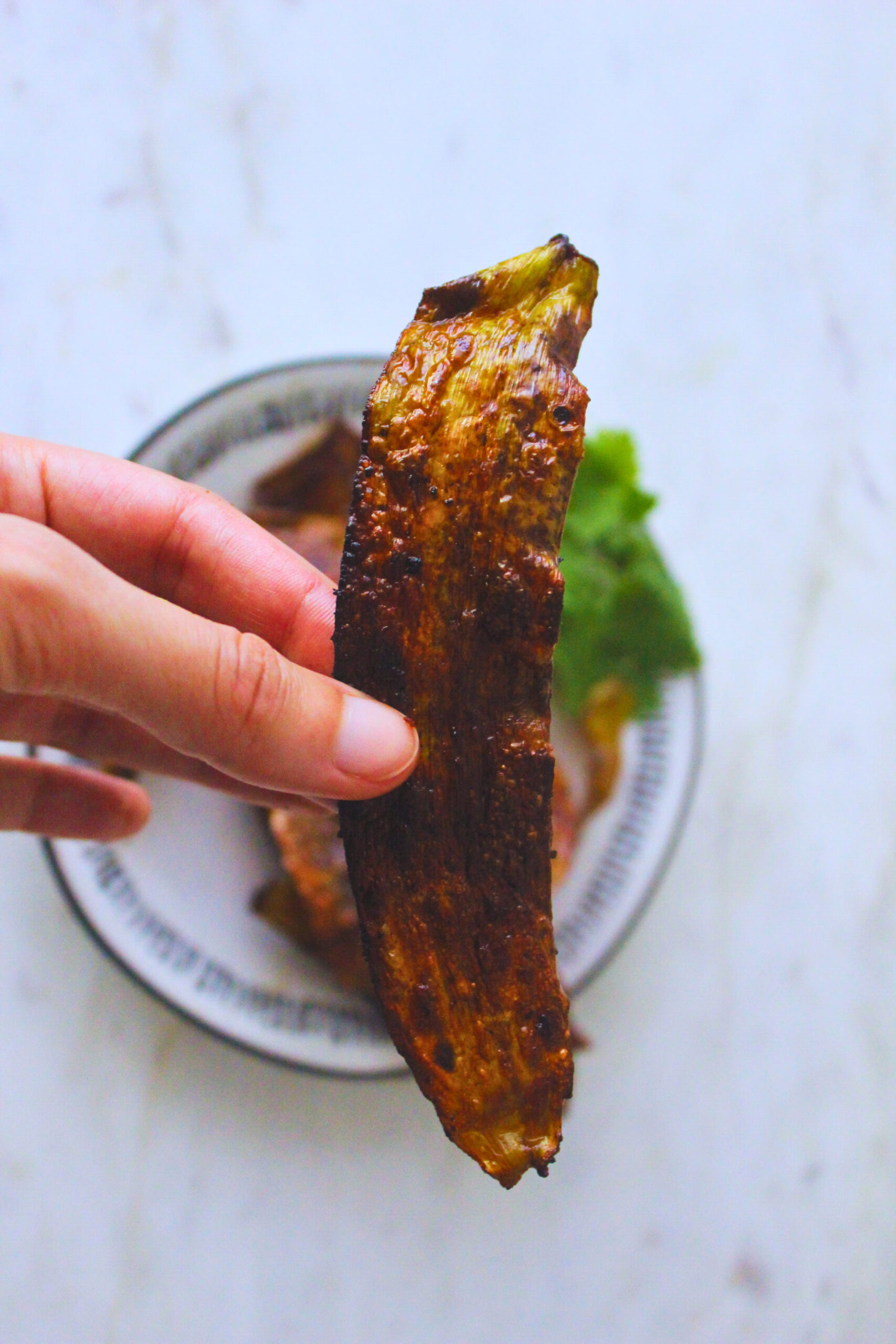 Image of a hand holding a strip of banana peel "bacon"