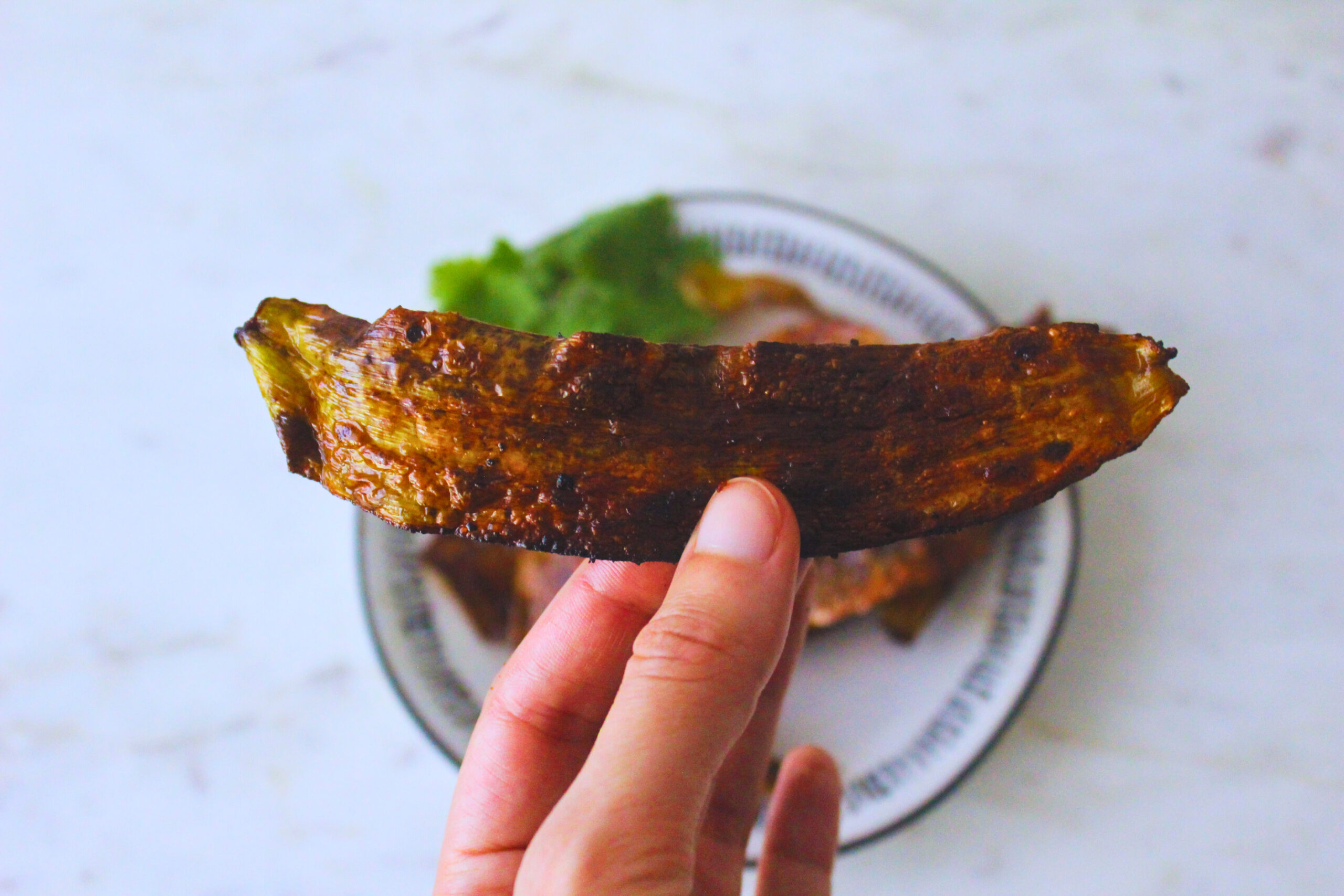 Image of a hand holding a strip of banana peel "bacon"