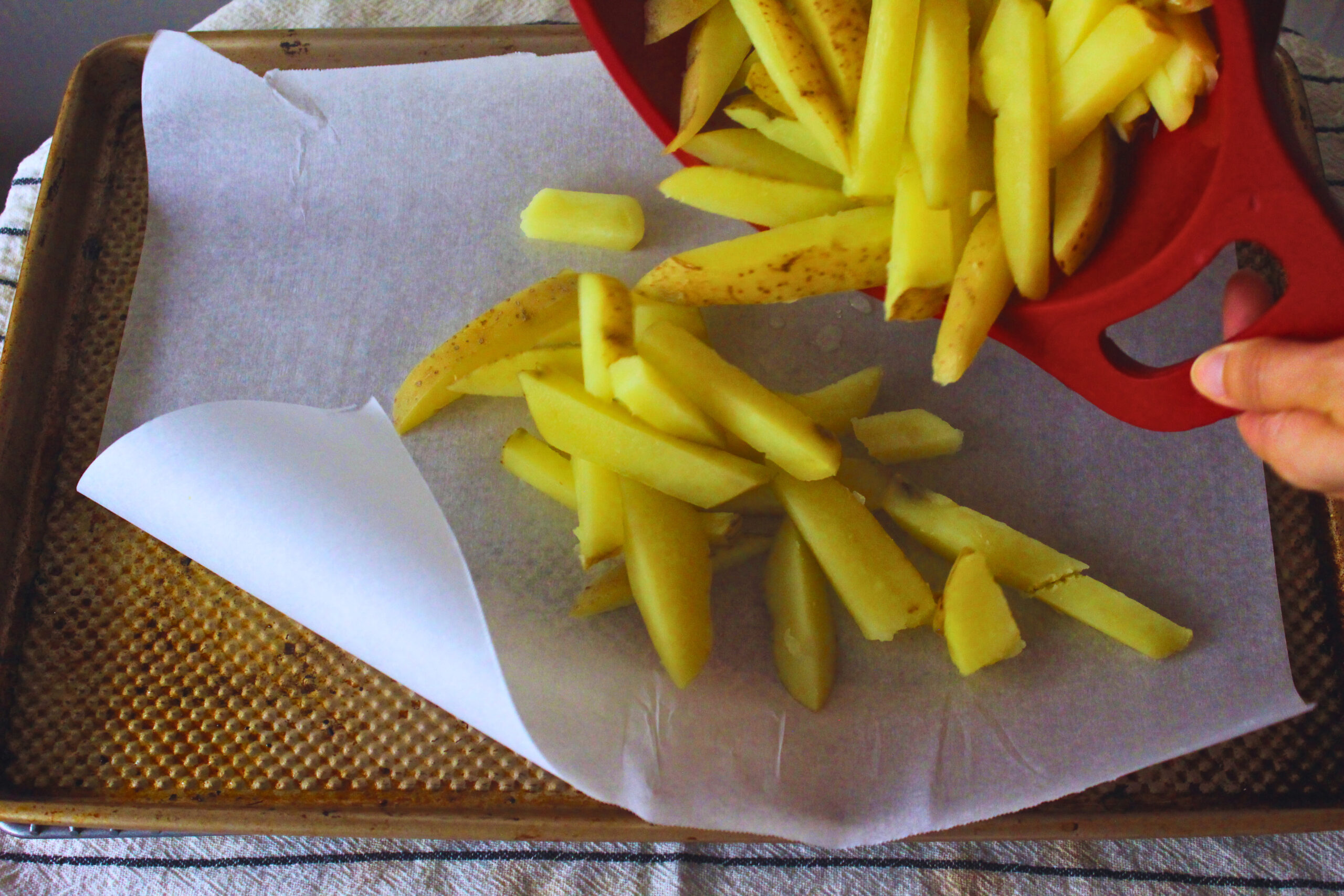 Boiled fries tossed onto sheet pan