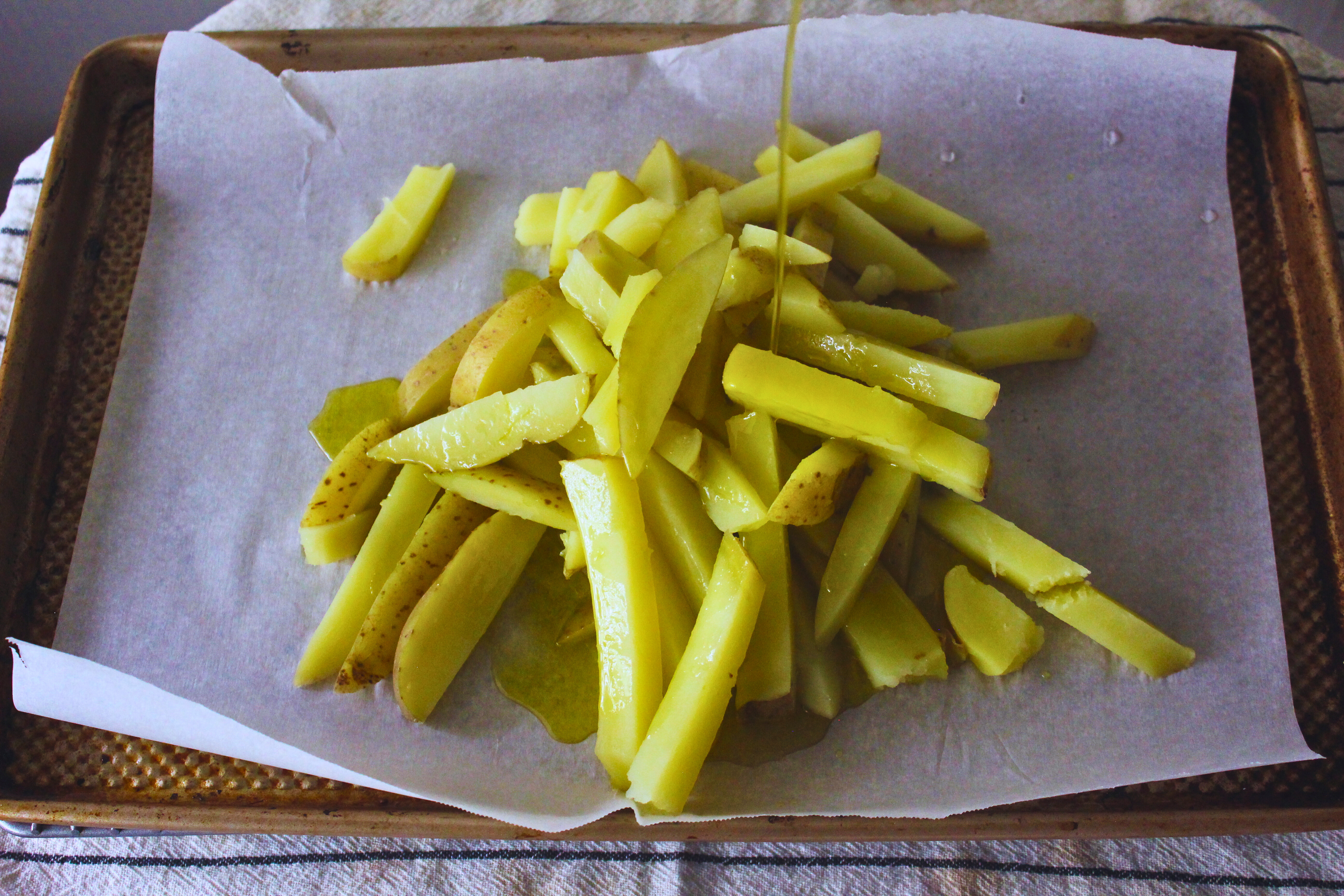 French fries being covered in olive oil
