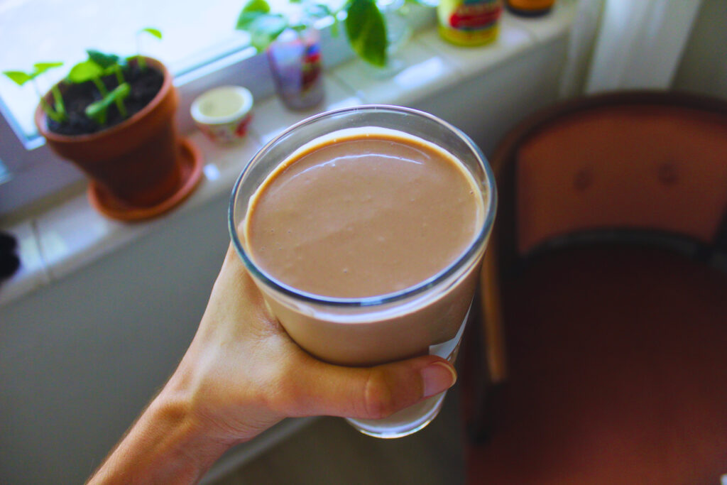 Image: Hand holding Glass filled with Chocolate Peanut Butter Banana Smoothie