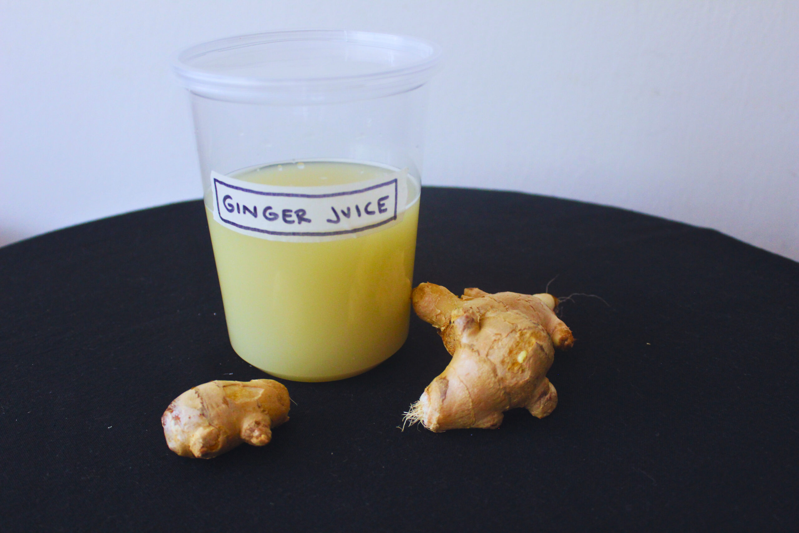 Image: Fresh ginger juice in container with fresh ginger root as decor