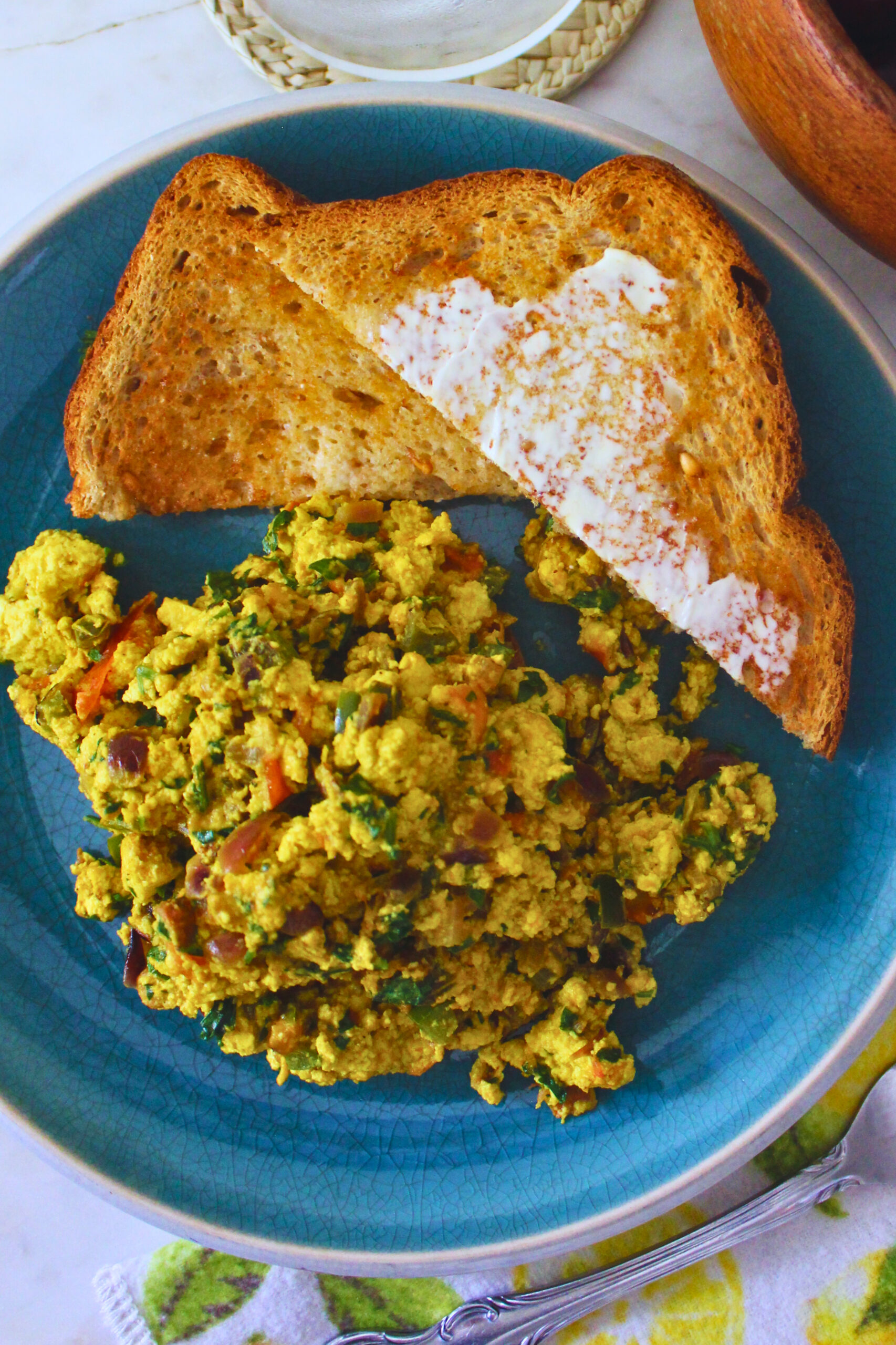 overhead image of tofu scramble with side of buttered toast on vibrant blue plate