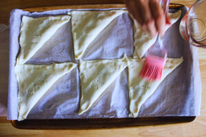 Image of simple syrup being spread on top of the pastries