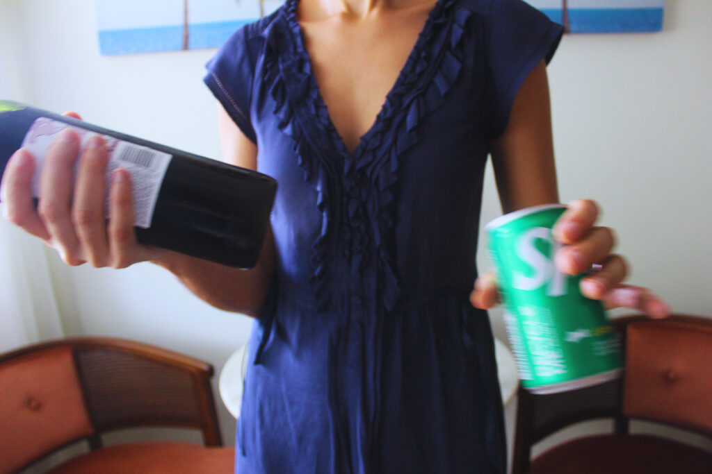 Image of a woman holding a bottle of wine and a can of lemon-lime soda