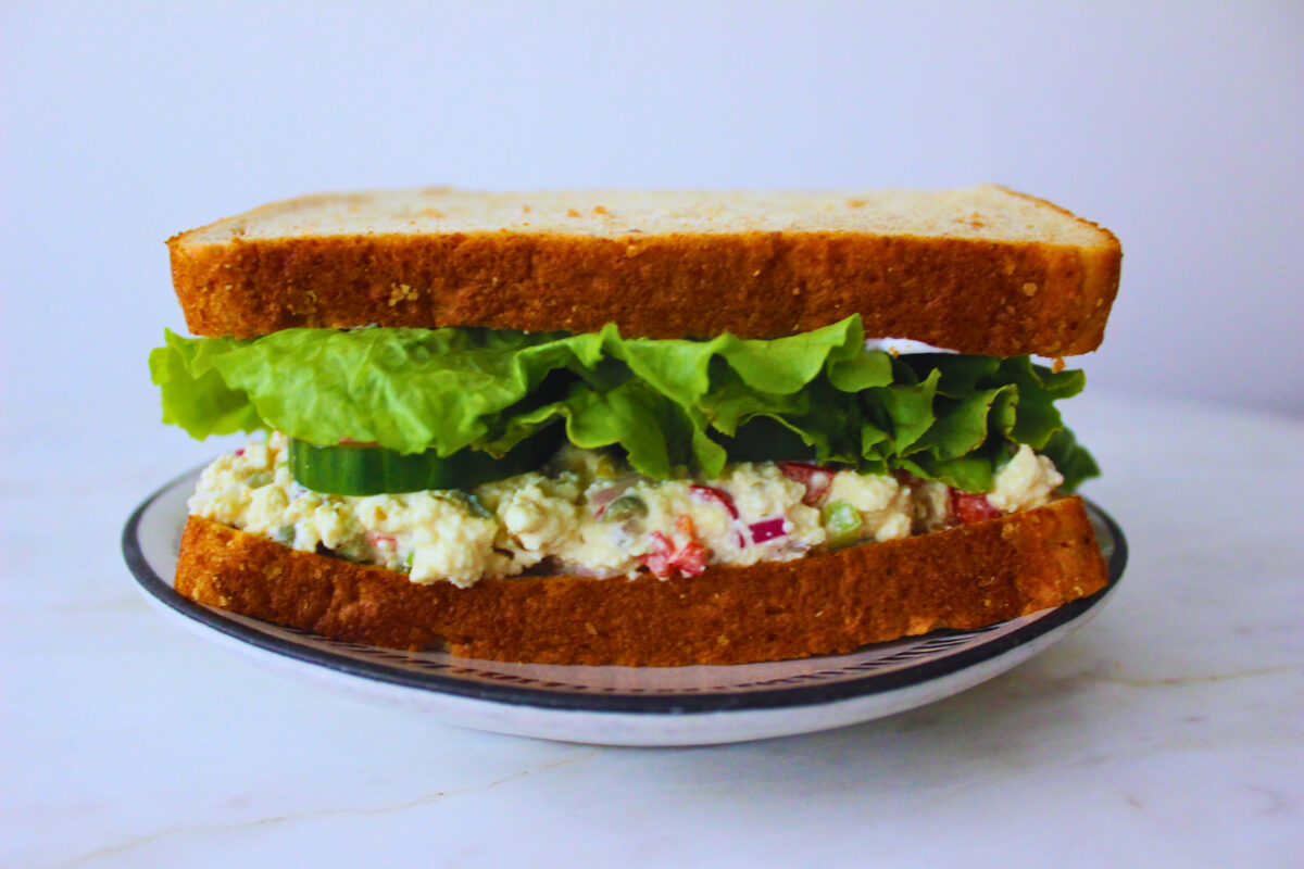image of tofu salad sandwich with lettuce, tomato, and cucumber