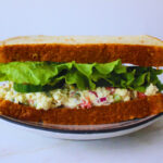 image of tofu salad sandwich with lettuce, tomato, and cucumber