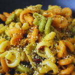 Close up image of lemon sundried tomato pasta with artichoke hearts, hemp seeds are sprinkled on it.