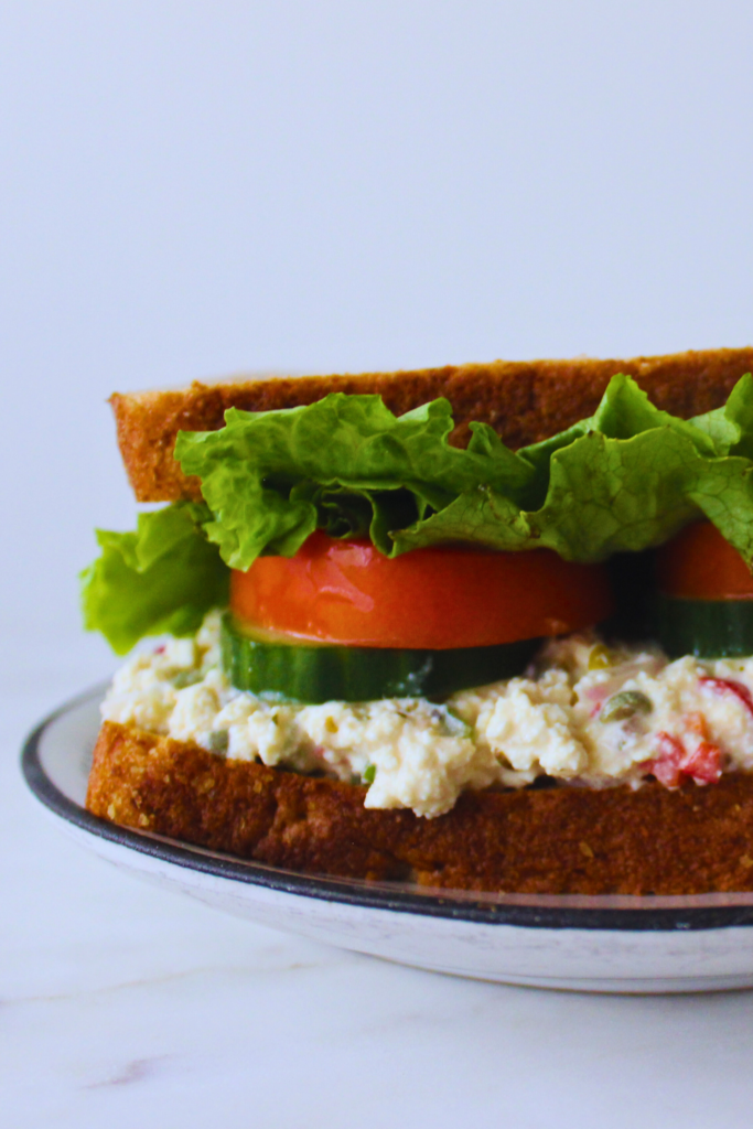 image of a prepared tofu salad sandwich with tomato, cucumber, and lettuce