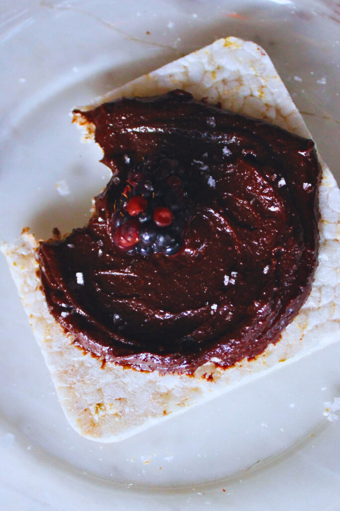 overhead image of rice cake with chocolate tahini spread topped with blackberry