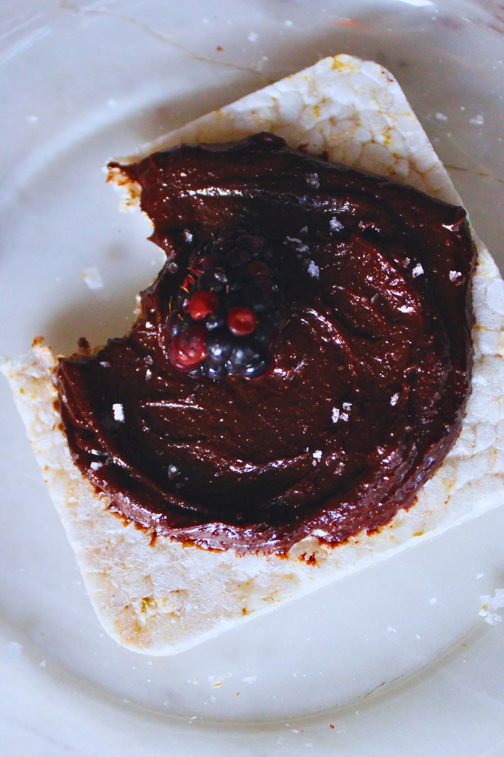 overhead image of rice cake with chocolate tahini spread topped with blackberry
