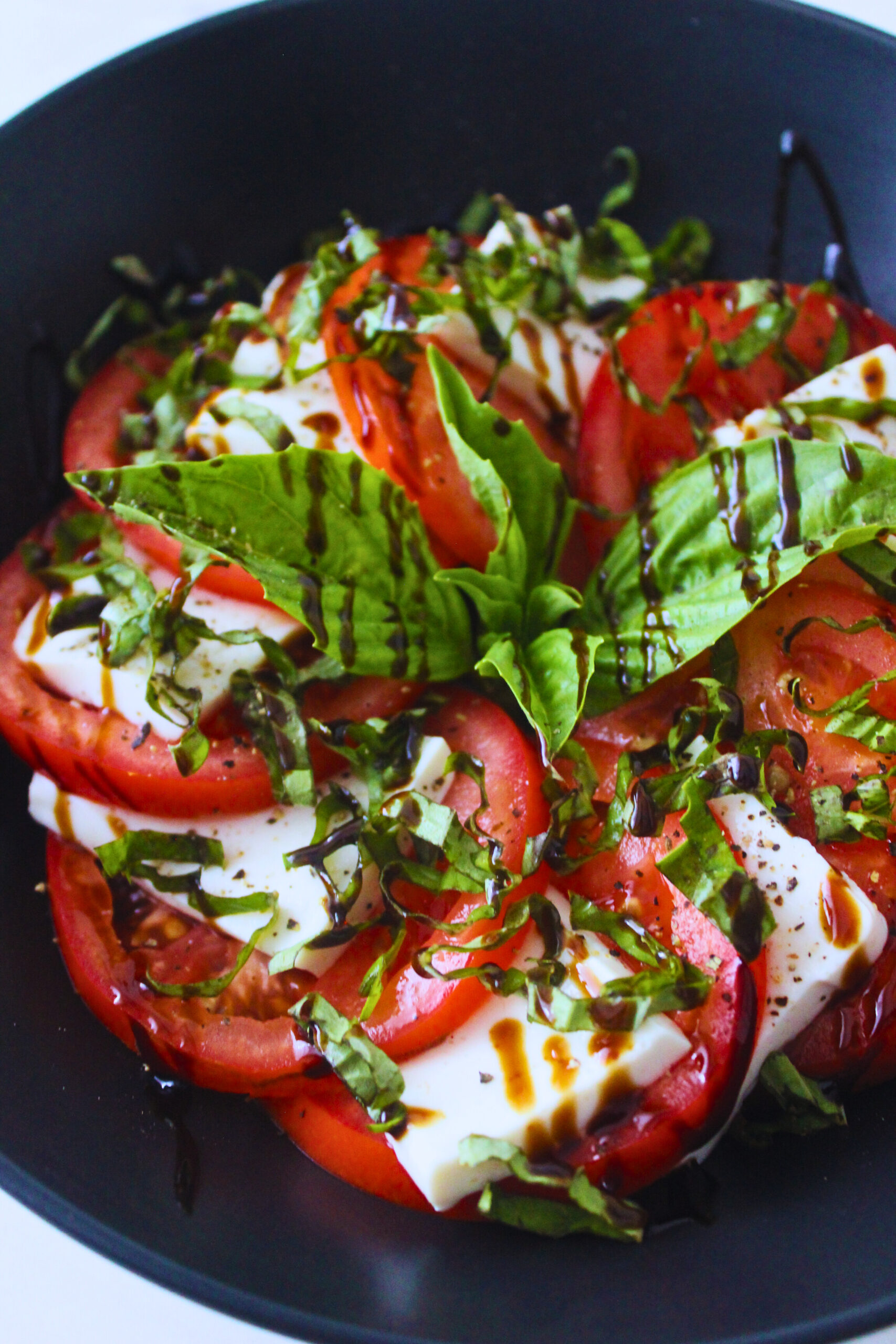 image of sliced tofu and tomato with fresh bail and a drizzle of balsamic vinaigrette