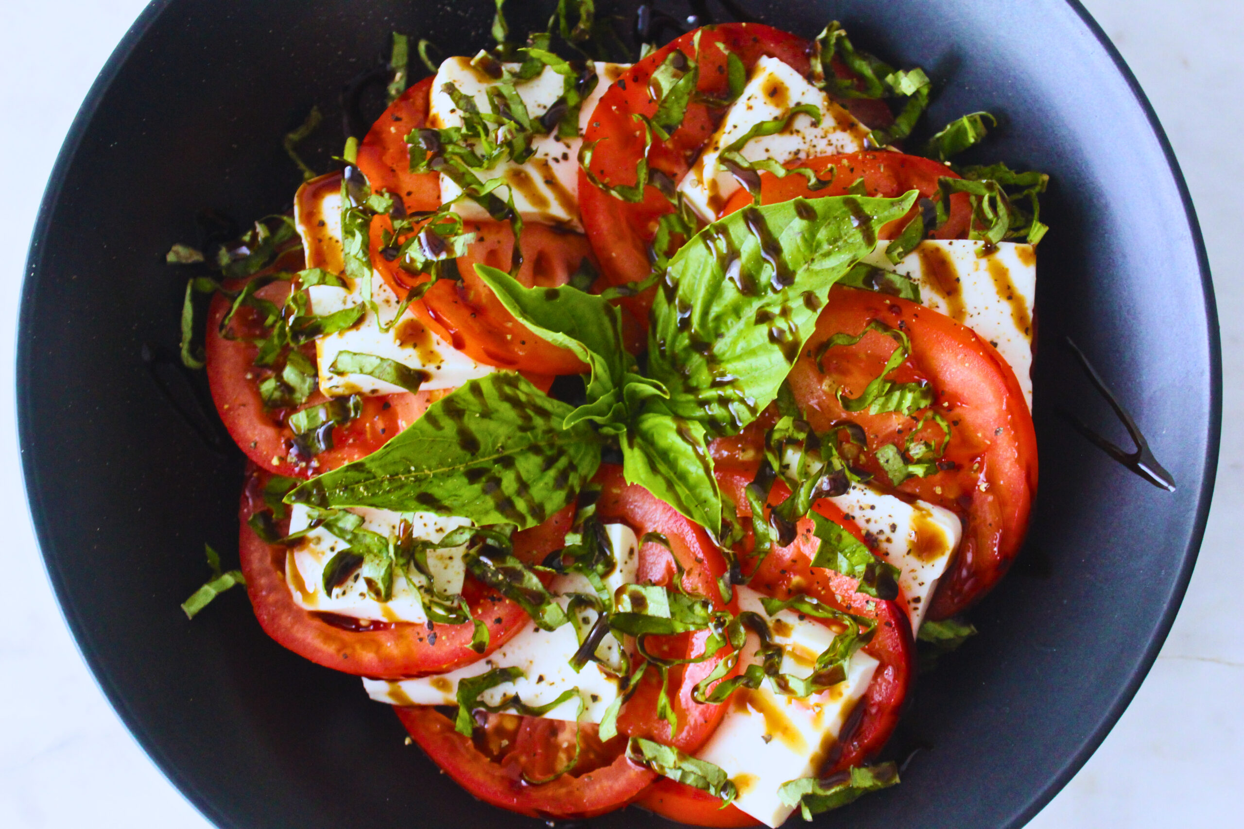 overhead image of tofu tomato basil caprese salad in blue plate.