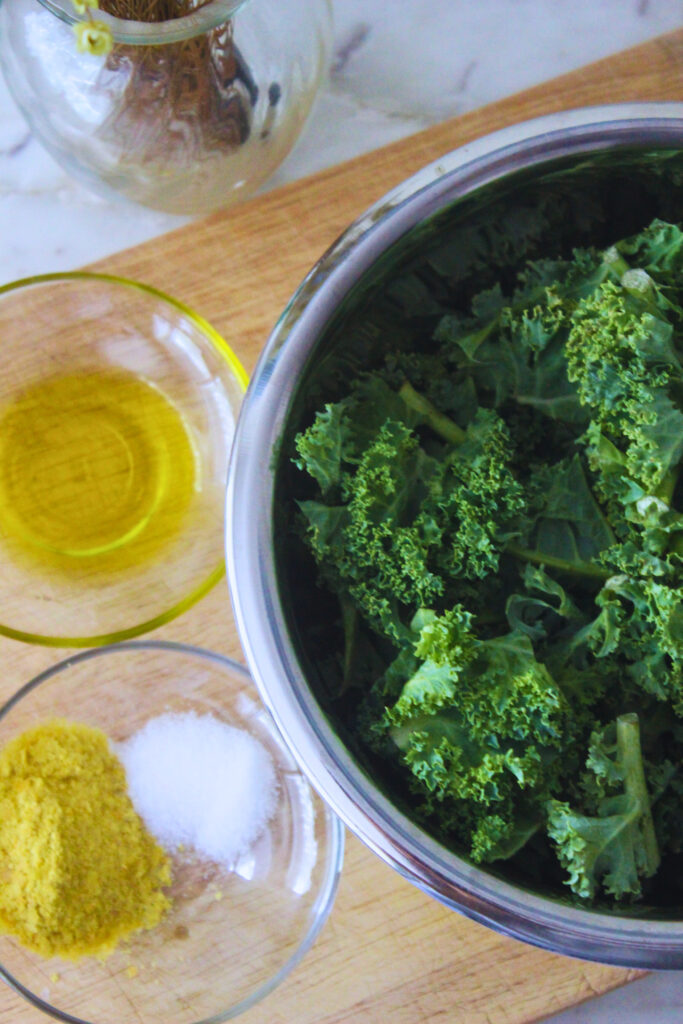 overhead image of ingredients for kale chips, kale, oil, salt and nutritional yeast.