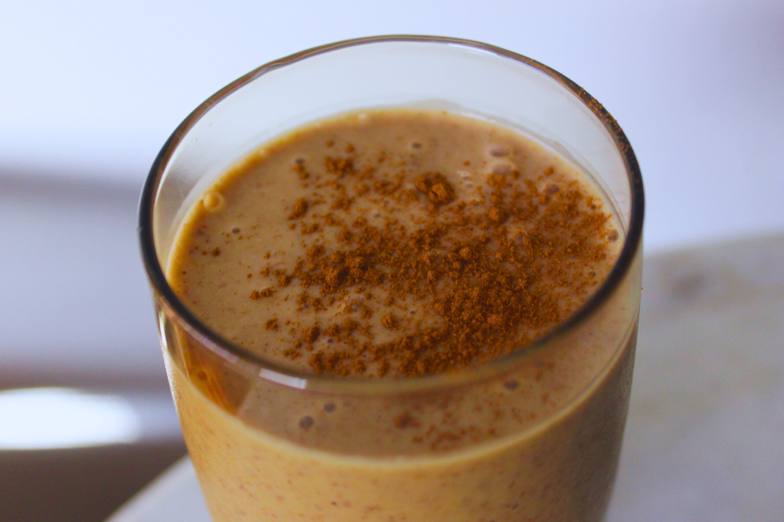 image of snickerdoodle smoothie in a glass topped with cinnamon powder