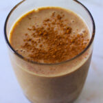 image of maca snickerdoodle smoothie in a tall glass topped with cinnamon powder