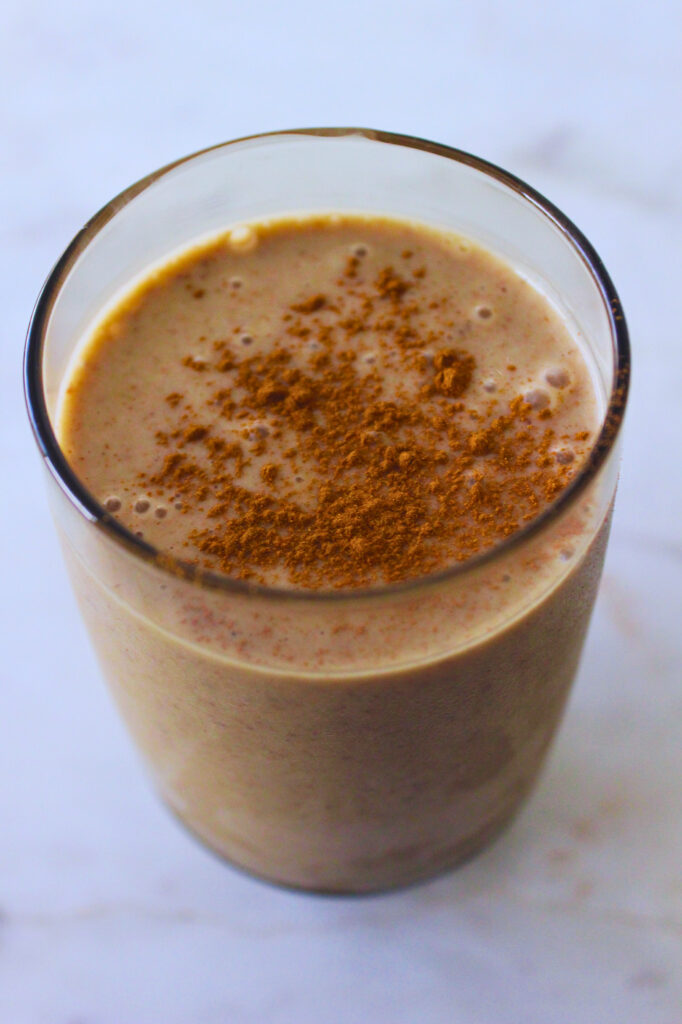 image of maca snickerdoodle smoothie in a tall glass topped with cinnamon powder