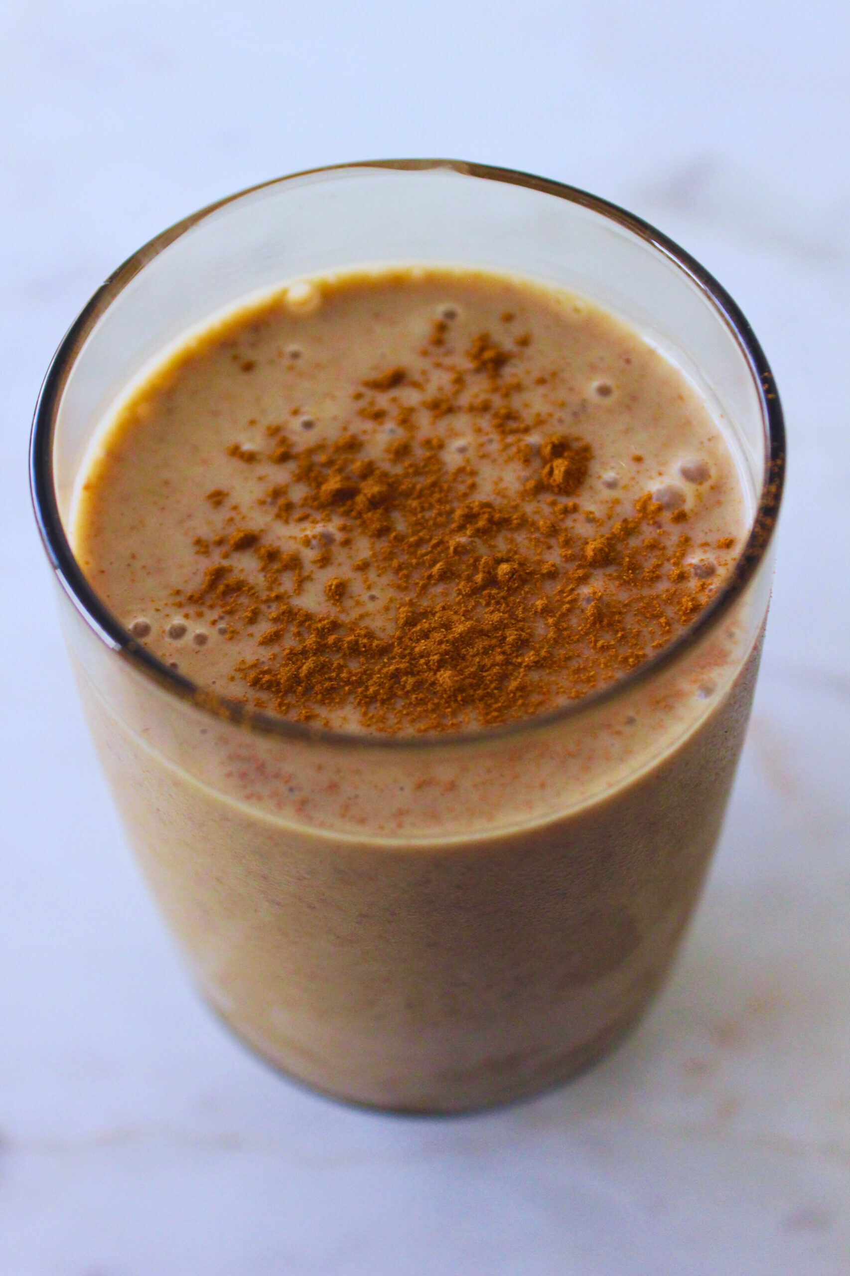 image of maca snickerdoodle smoothie in a tall glass topped with cinnamon powder