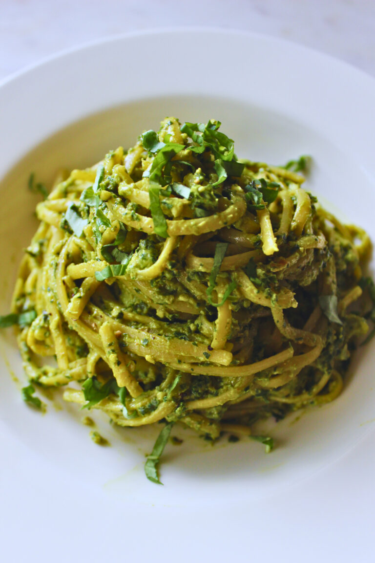 vegan Peruvian tallarines verde. Peruvian pesto served on a white plate topped with fresh basil