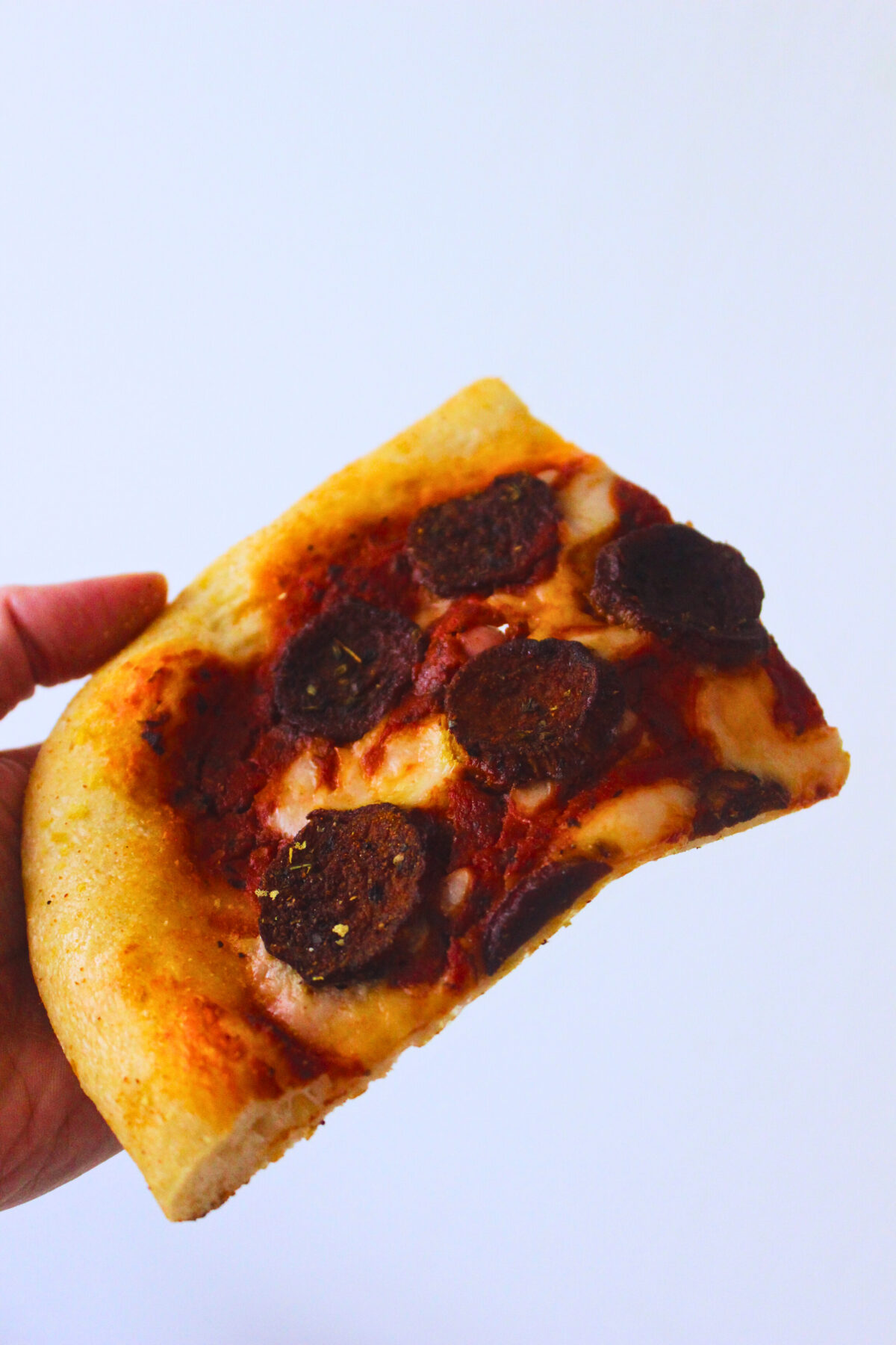 image of a slice of pizza with vegan pepperoni made from mushrooms