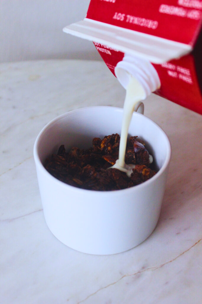 image of soy milk being poured over a cup of chocolate granola