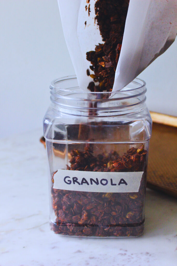 image of homemade chocolate granola being put into a storage container