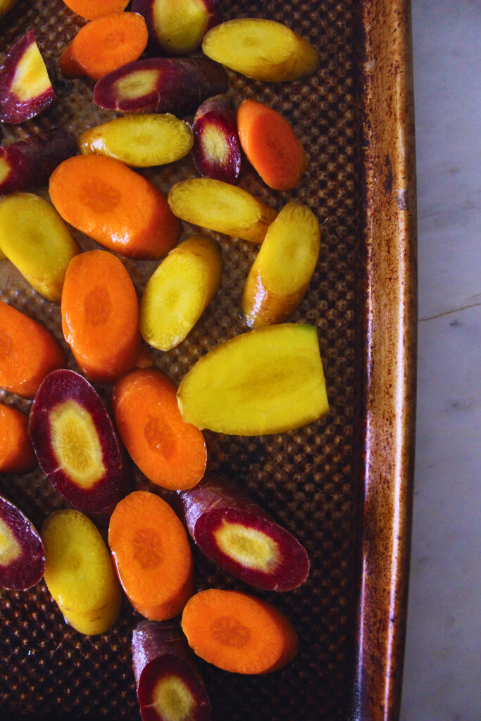 sliced rainbow carrots spread on a baking sheet