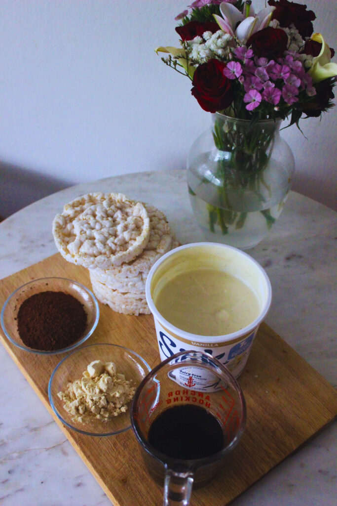 image of ingredients to make vegan no-bake tiramisu on a marble table top with a vase of fresh flowers