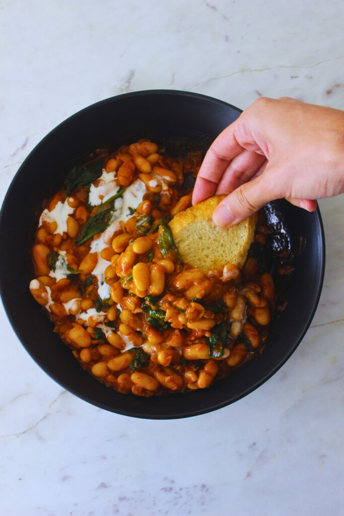 overhead image of bread being dipped into creamy white beans