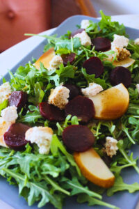 image of a plate with arugula beet salad on a marble bistro table