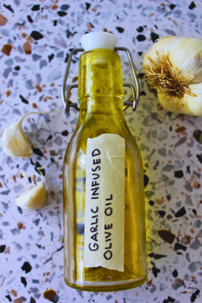 overhead image of fresh garlic and a glass bottle filled with garlic infused oil