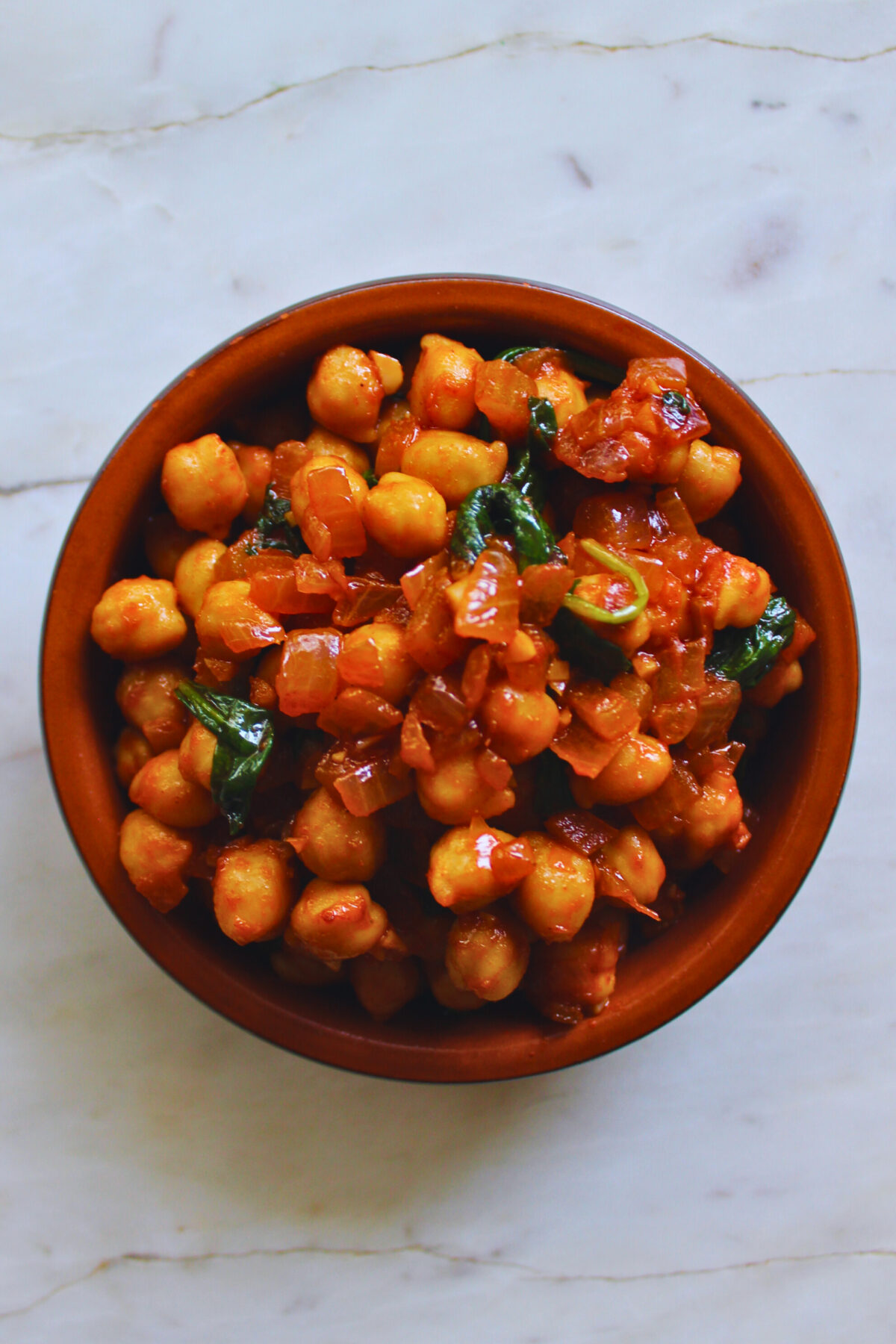 overhead image of chickpeas and spinach served in a Spanish ceramic tapa dish