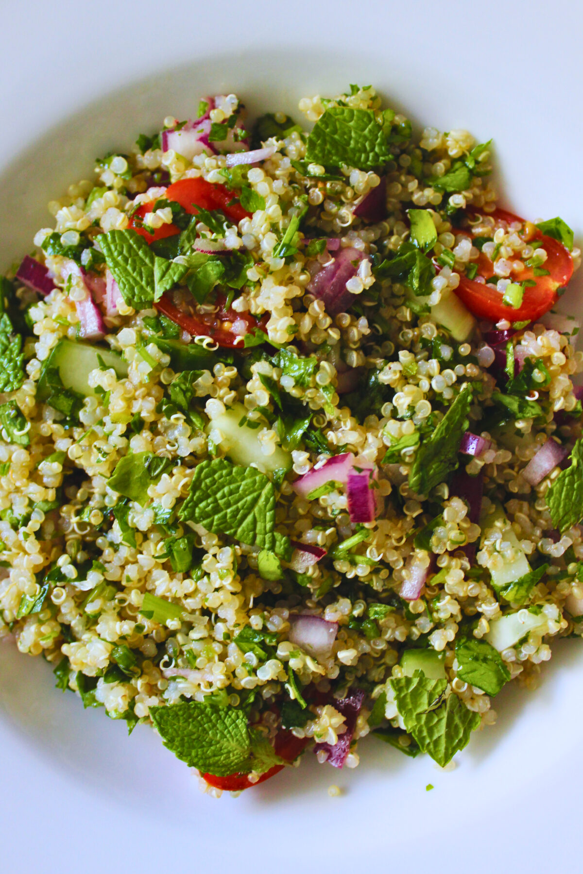 overhead image of refreshing quinoa tabbouleh salad served on a white plate